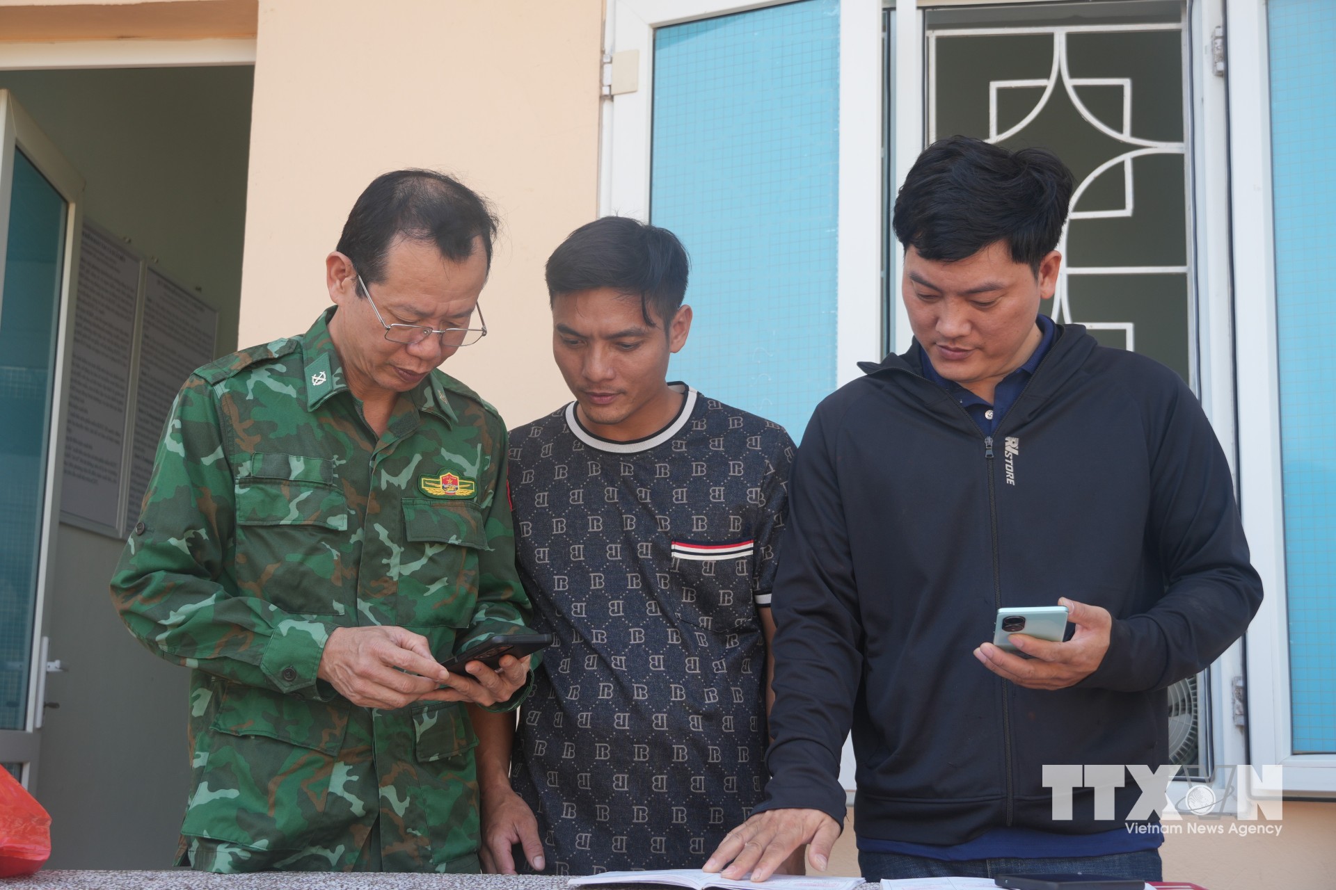 Cán bộ Đồn Biên phòng Hoằng Trường, tỉnh Thanh Hóa, hướng dẫn ngư dân tải app ứng dụng eCDT. (Ảnh: Hoa Mai/TTXVN)